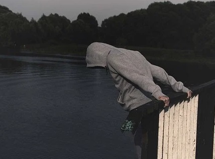 Jovén en actitud suicida frente a un puente