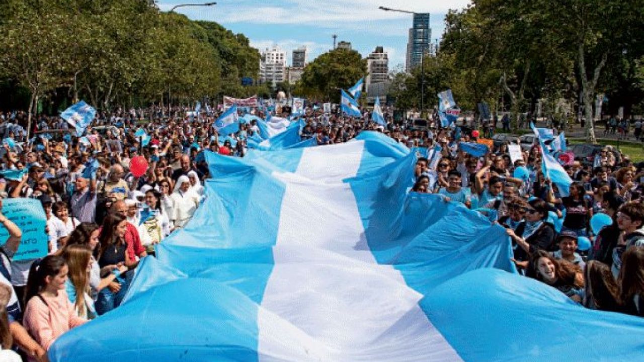Argentinos llevando una gran bandera argentina.